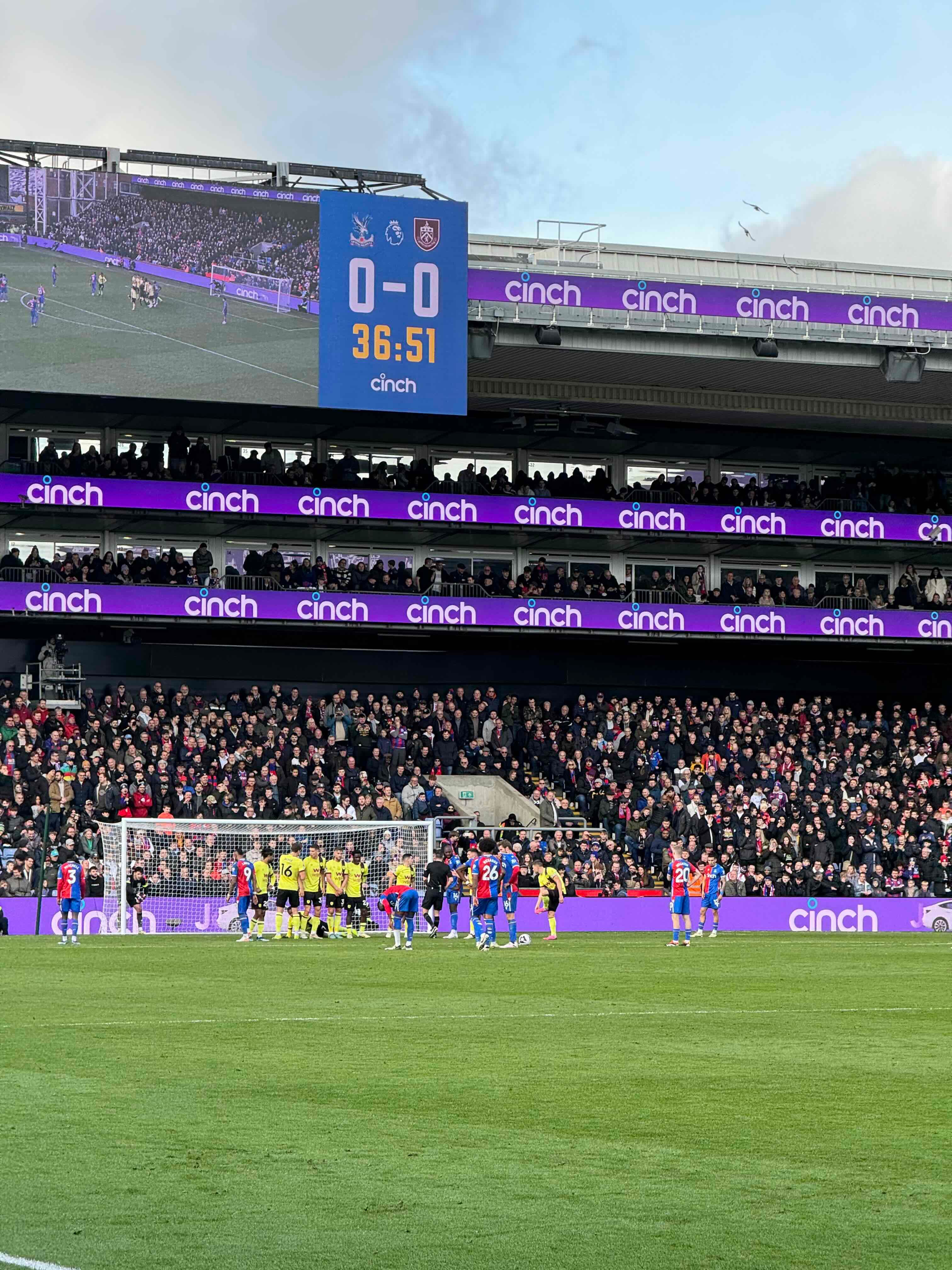 Crystal Palace match at Selhurst Park with players lined up for a free kick and a full crowd in the stands.