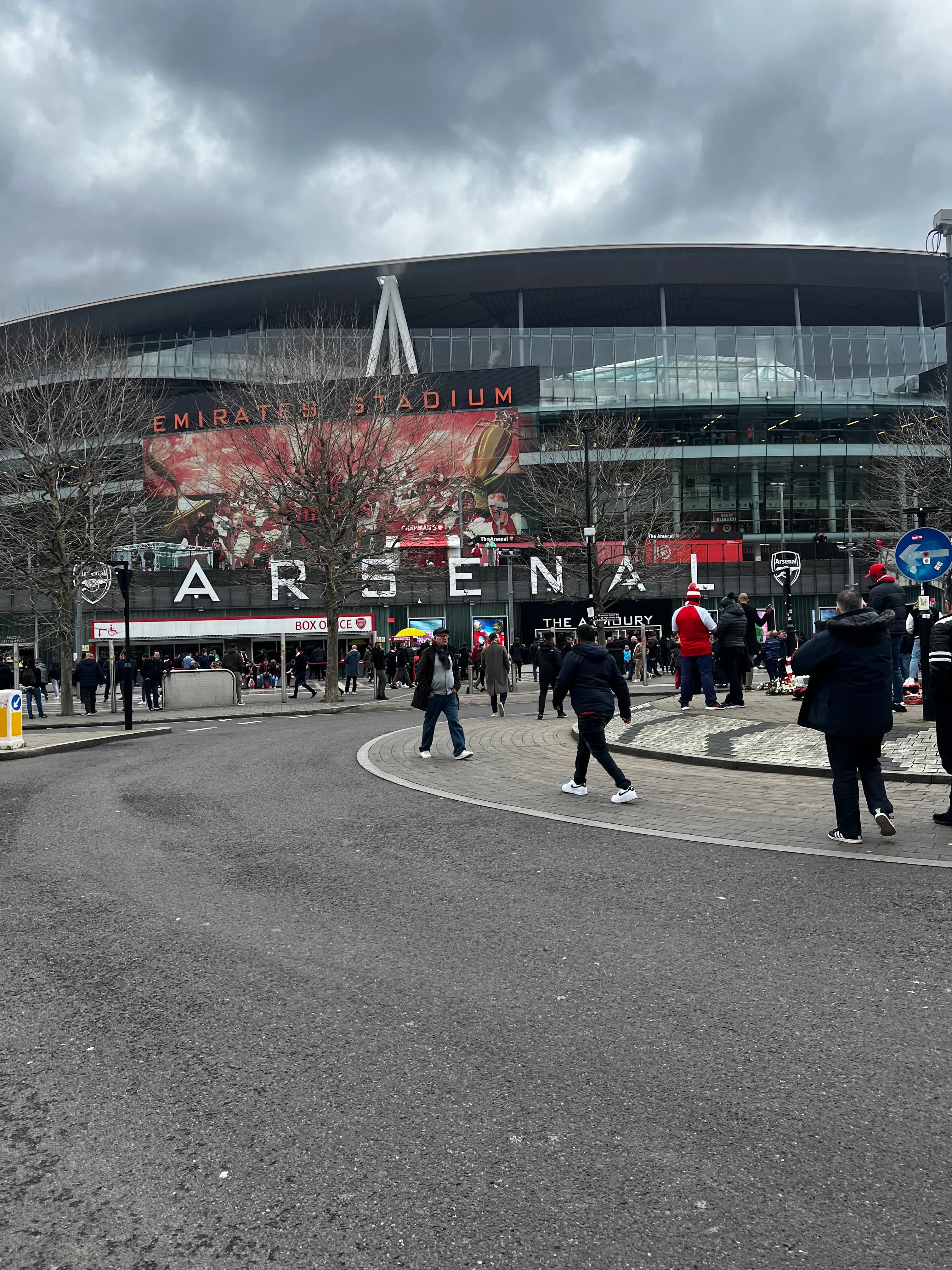 Emirates Stadium main entrance with Arsenal lettering box office and The Armoury store fans arriving on matchday