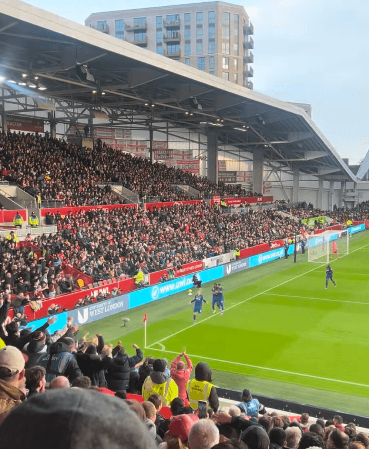 Away fans celebrating a goal in the northeast corner of the Gtech Community Stadium.